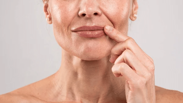 Closeup Shot Of Middle Aged Woman With Wrinkles On Face Touching Lips With Finger, Unrecognizable Mature Female With Bare Shoulders Posing Over Light Grey Studio Background, Free Space