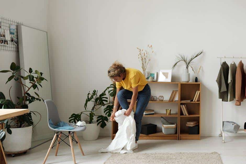A woman arranging decor in a living room with warm hardwood flooring