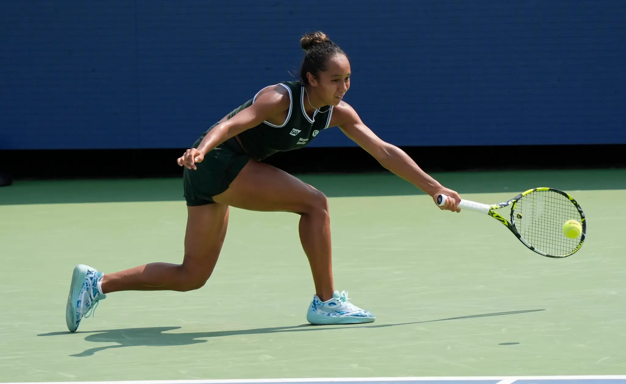 Tennis player in action reaching for a ball on outdoor court in daylight
