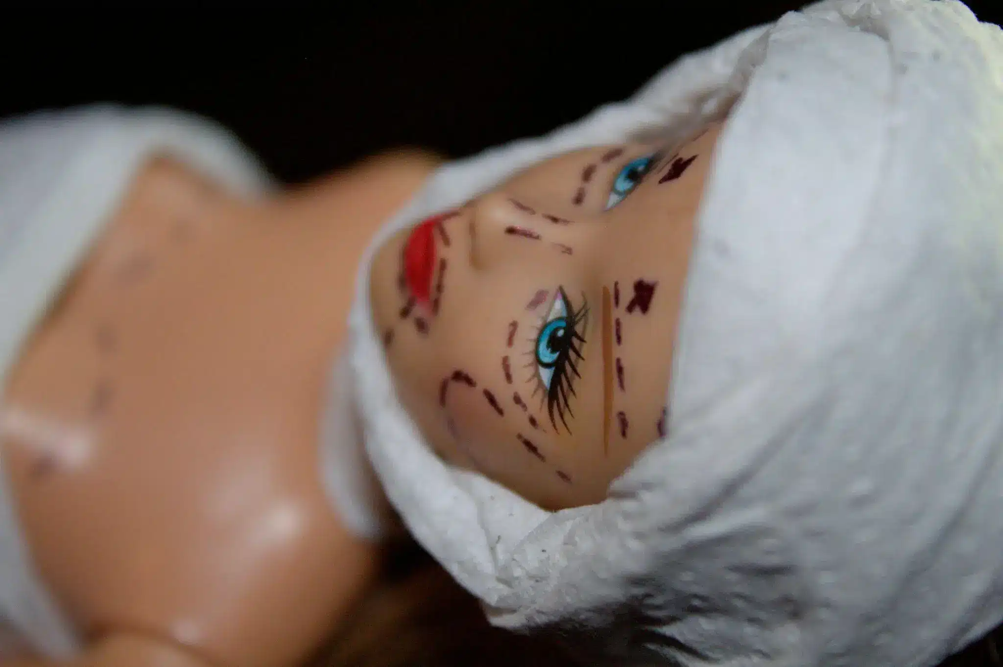Plastic doll head with marked surgical lines and bandages in close-up view