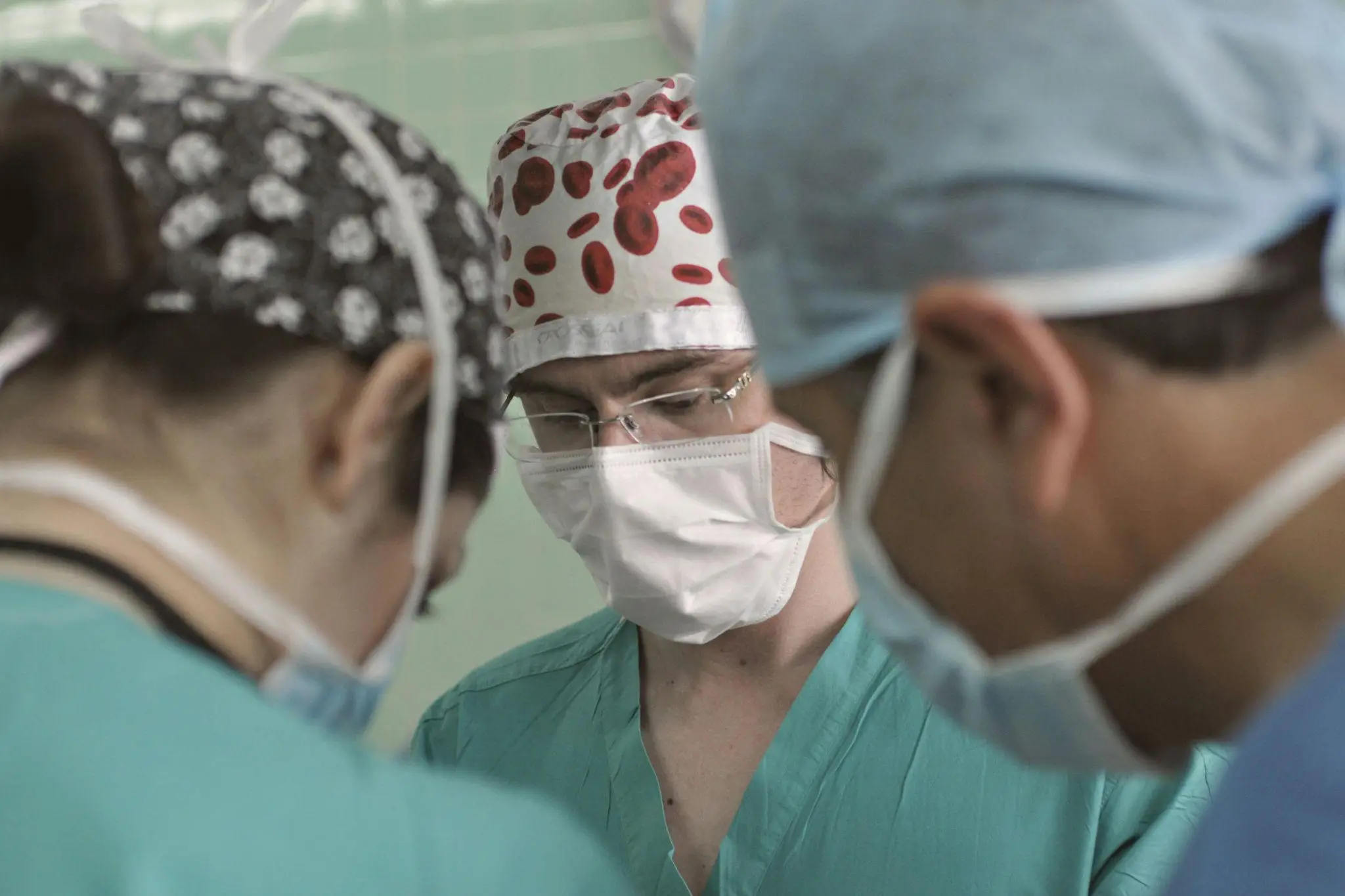 Medical team in surgical scrubs and masks focusing on operation in bright hospital room