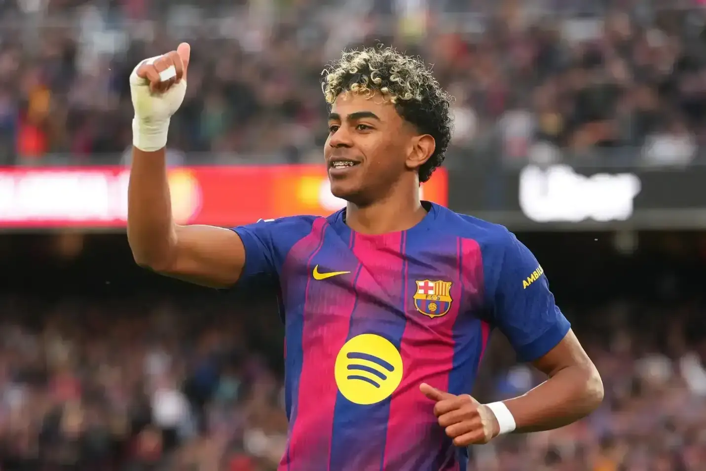 Soccer player celebrating in a vibrant stadium wearing blue and pink striped jersey