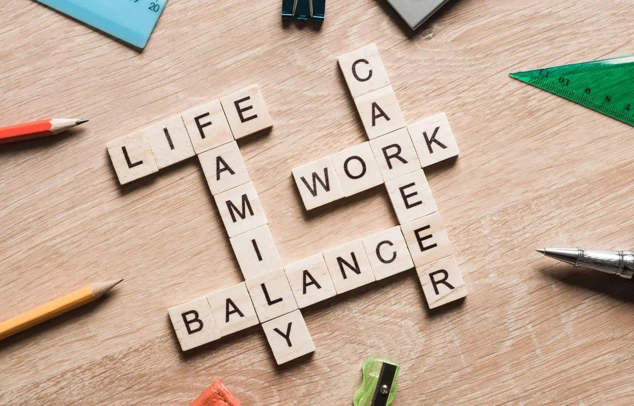 Scrabble tiles forming words life, family, work, career on wooden table with stationery items