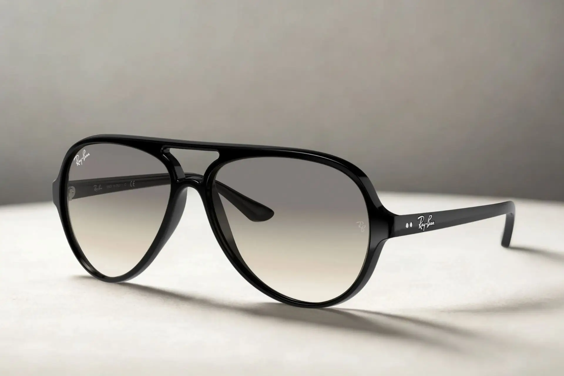 Black sunglasses with gradient lenses on light gray surface in soft lighting