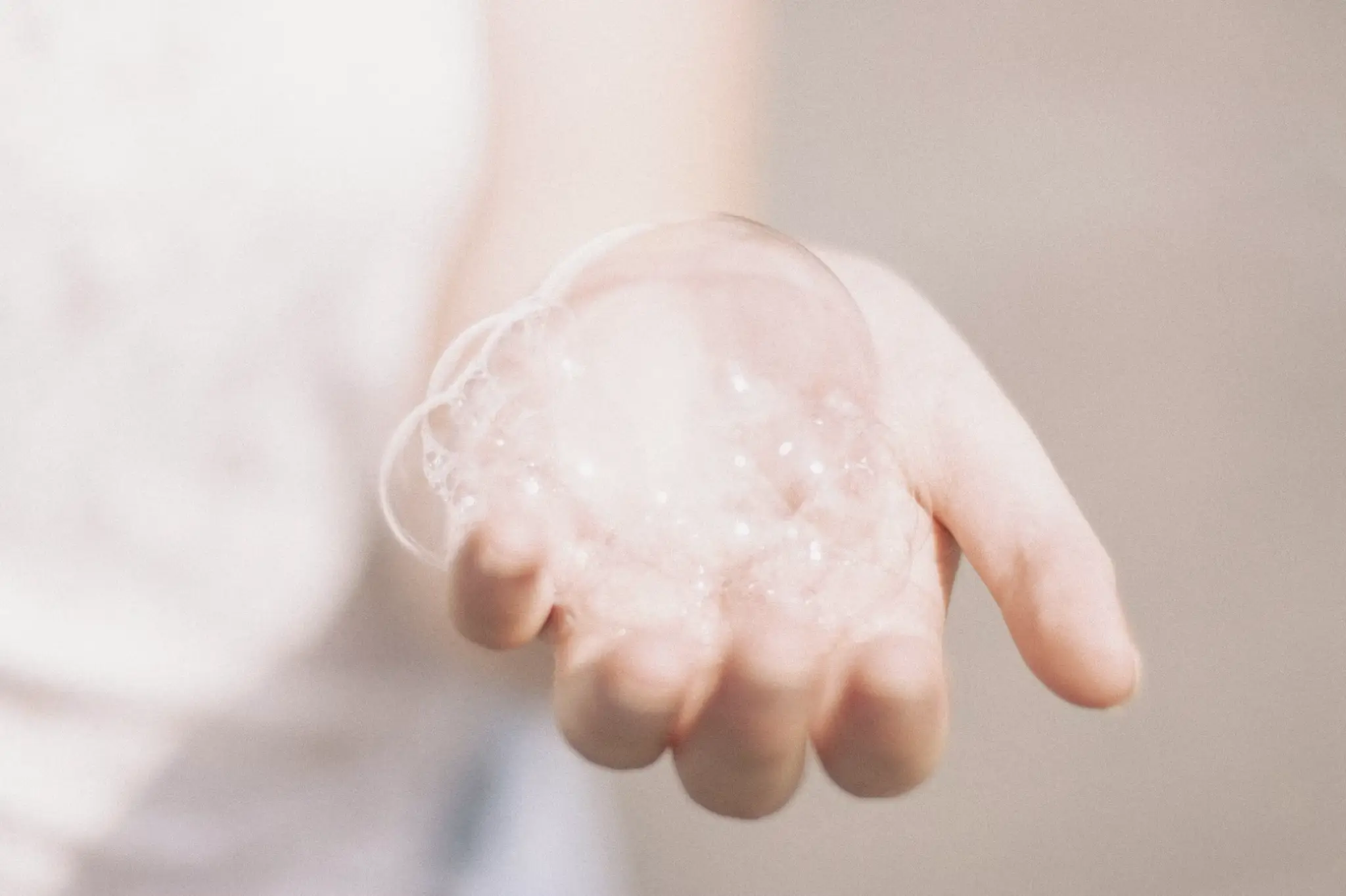 Hand holding translucent soap bubbles in bright lighting