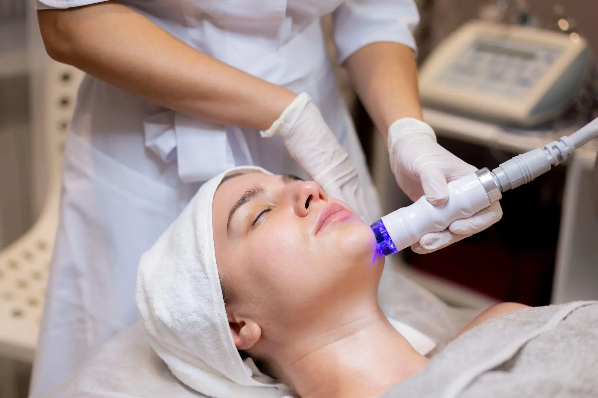 Aesthetician performing facial treatment with LED device in a clinic setting