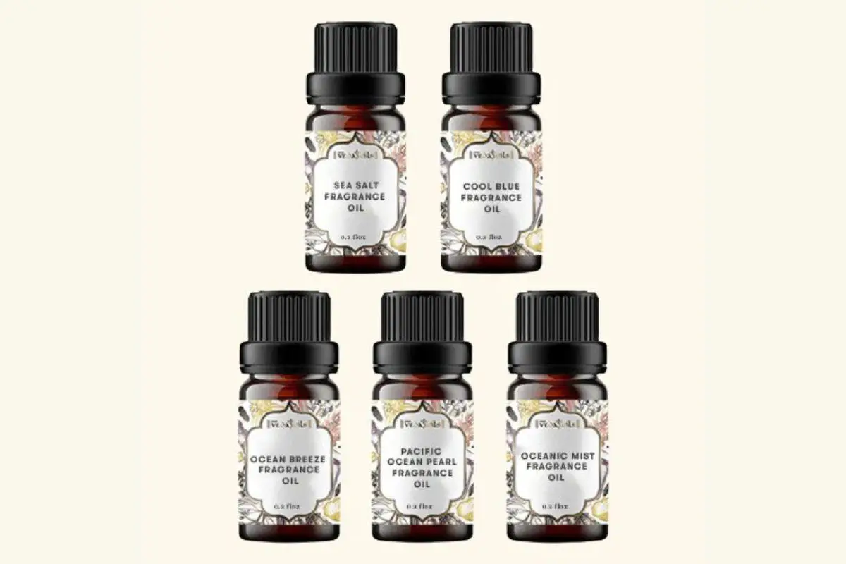 Five bottles of fragrance oils with decorative labels on a plain background