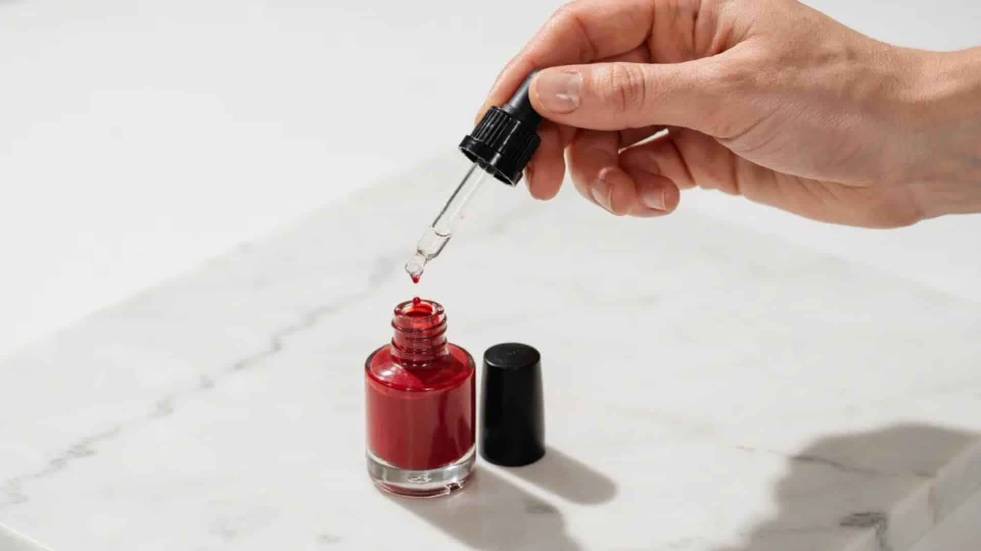 Adding more clear thinner drops into deep cherry red nail polish to adjust consistency