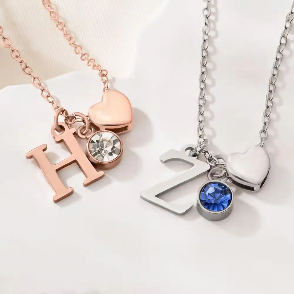 Two necklaces with heart charms and letter pendants on white background