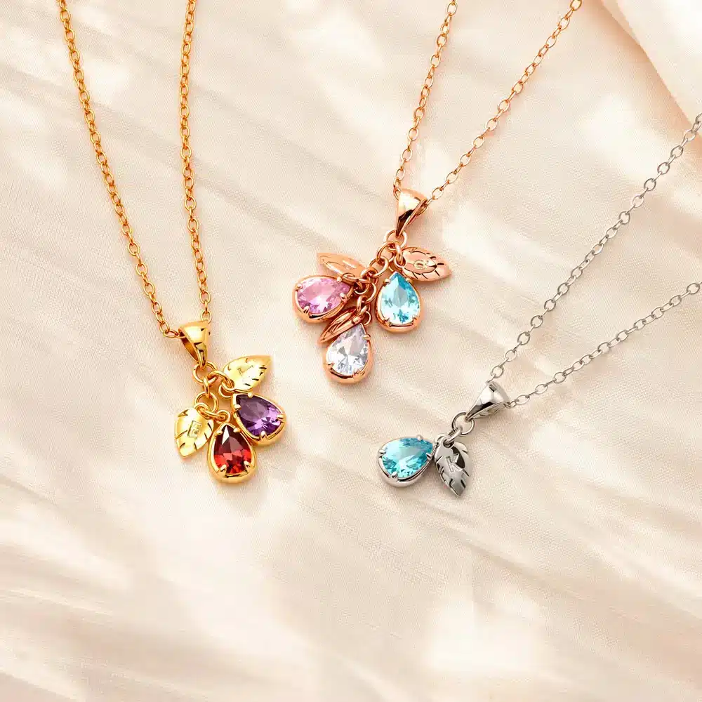 Three gemstone necklaces with gold and silver chains on a light fabric background