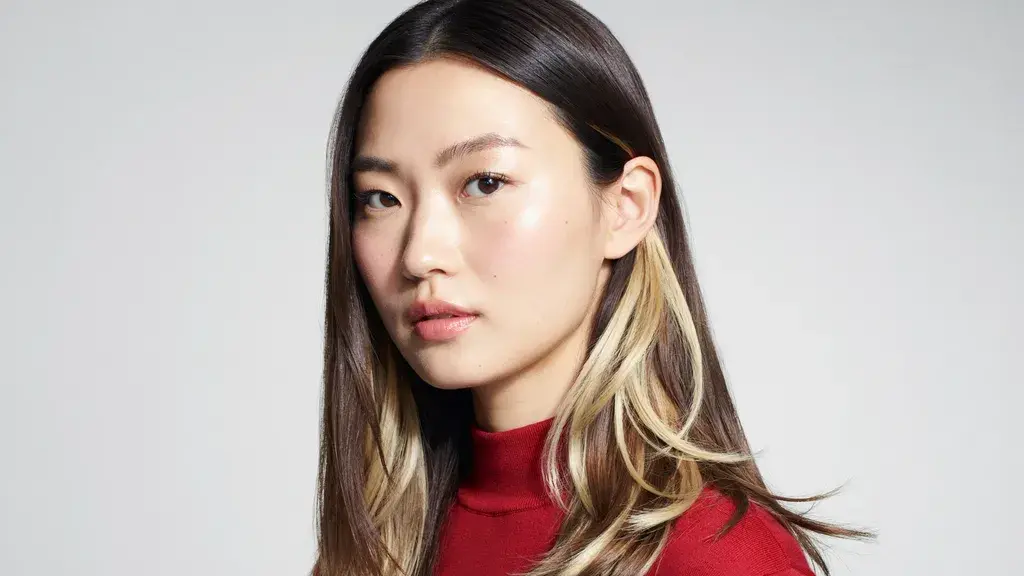 Dark brown hair with blonde peekaboo highlights styled in a sleek layered cut with contrasting light strands and smooth texture