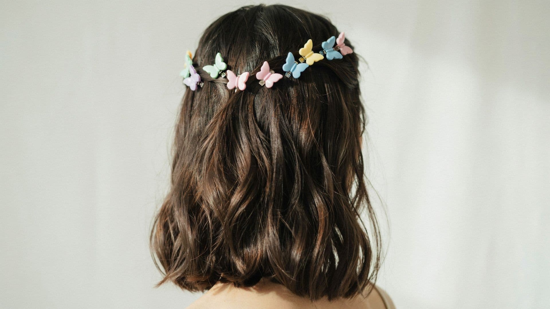 Y2K hairstyle with colorful butterfly clips placed along the crown of long glossy hair.
