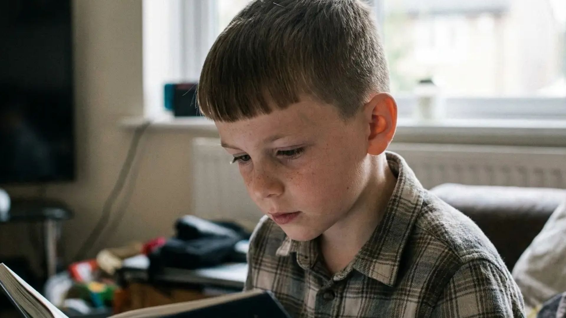 Young boy with Caesar cut hairstyle featuring straight blunt fringe and clean tapered sides in a barber shop setting.