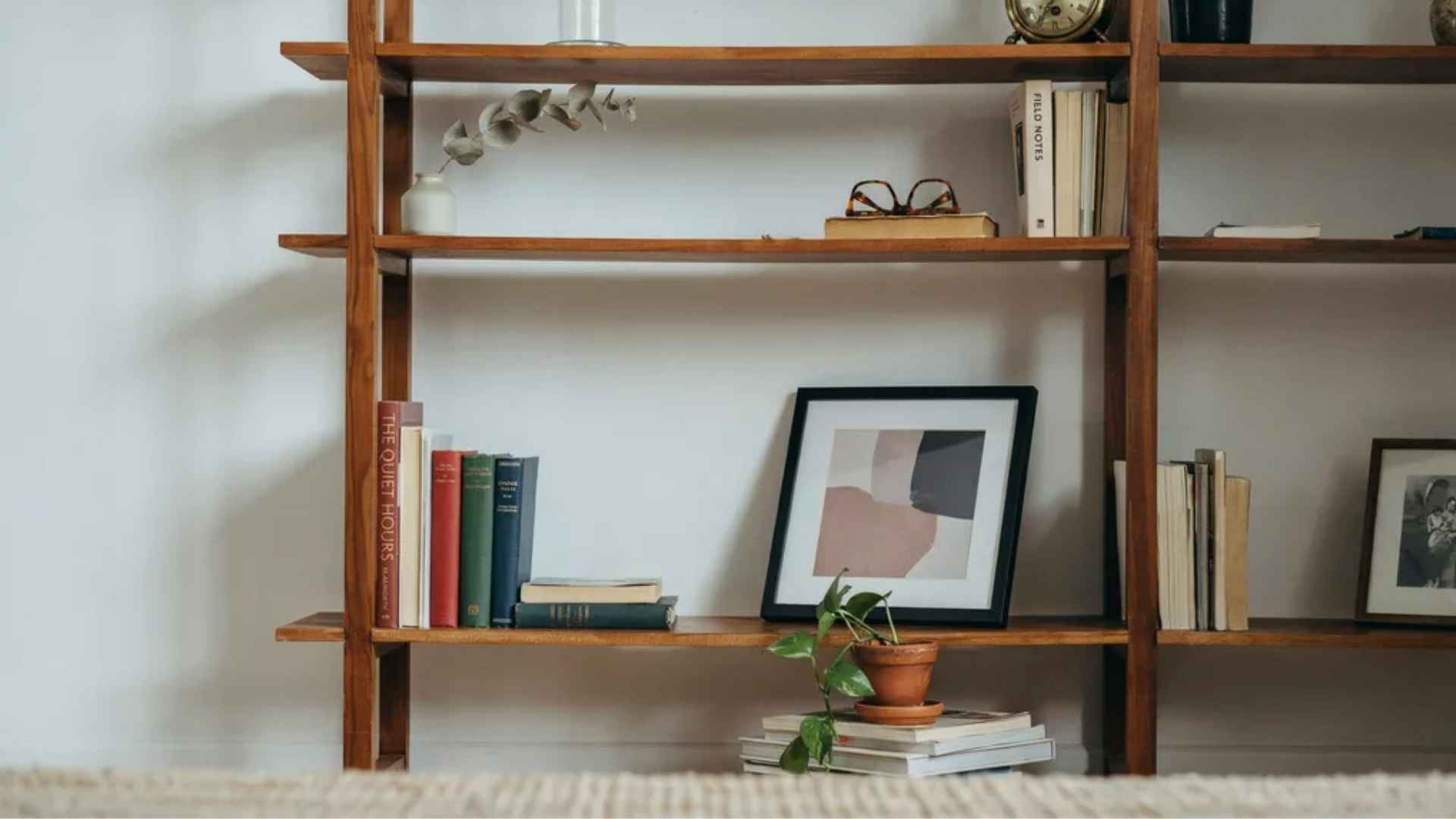 Framed art leaned at eye level as the focal point of a styled bookshelf