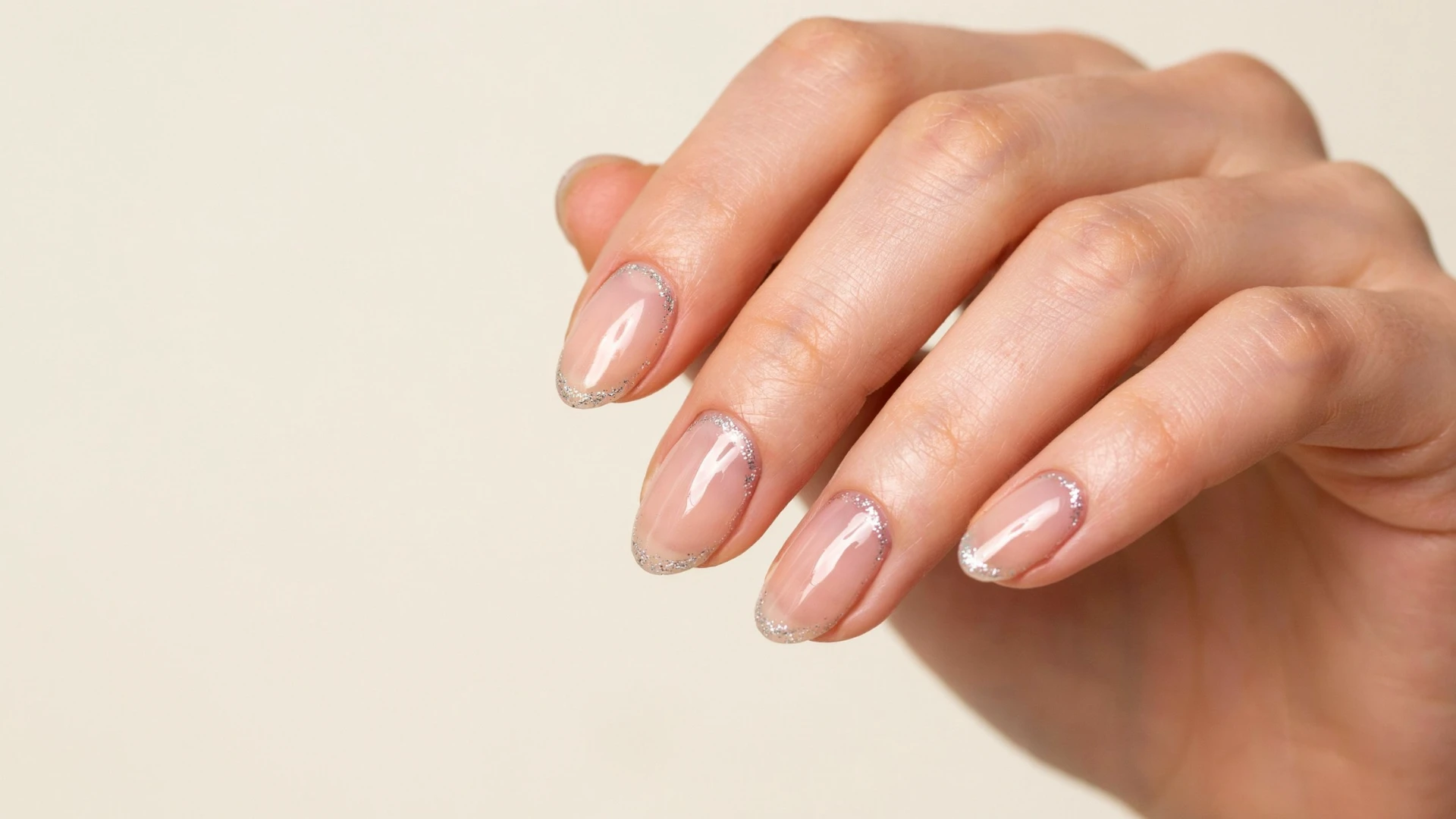Close view of elegant nude nails decorated with colorful French tips creating a simple modern nail art style