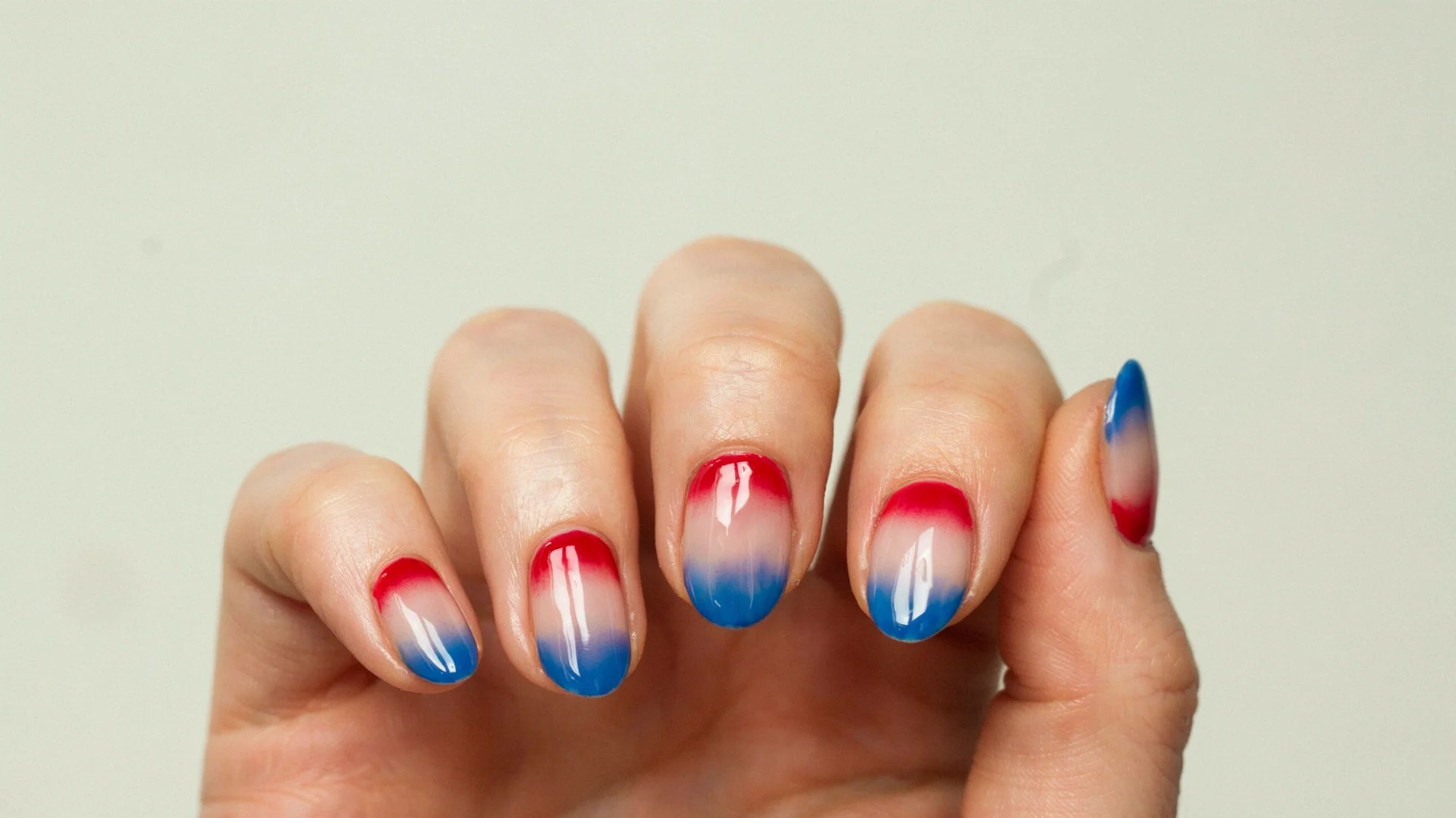 Glossy gradient nail art featuring bold red and blue colors with a soft white transition for a stylish manicure look