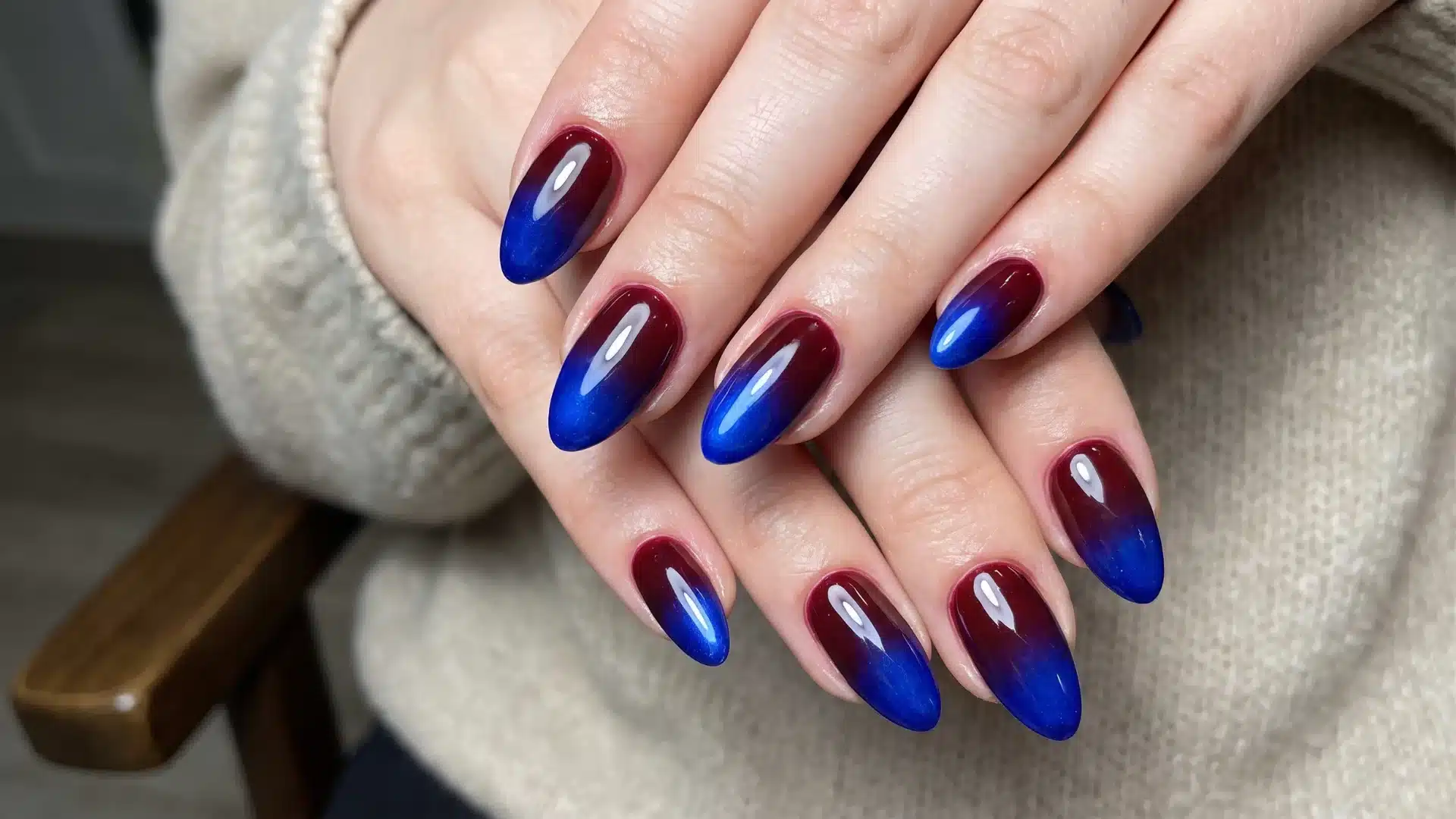 Bold ombre manicure featuring rich wine red tones blending into bright blue tips on long glossy nails