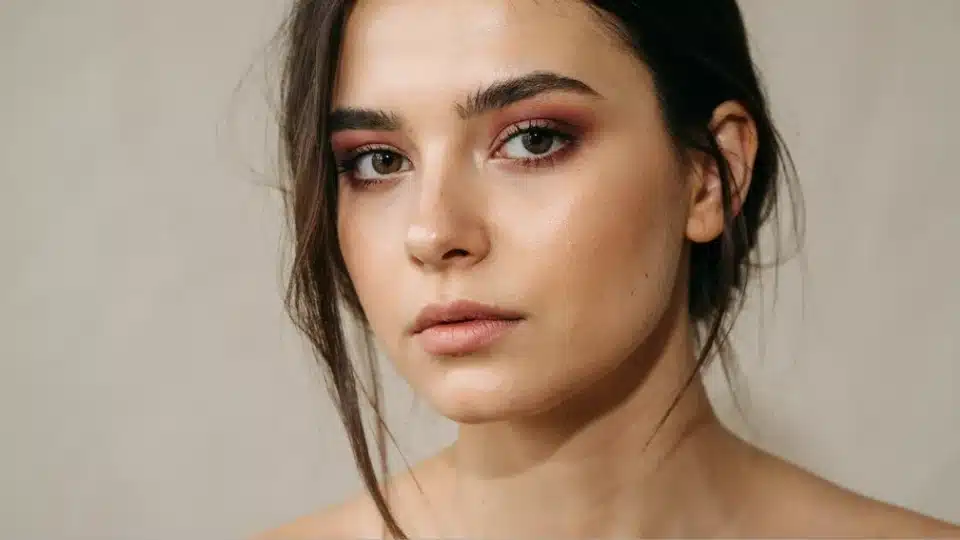 Woman wearing deep burgundy eyeshadow blended lightly across the eyelids for a refined everyday look.
