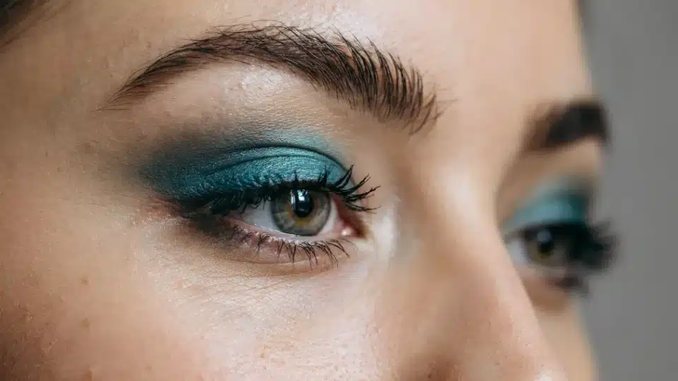 Woman wearing deep teal eyeshadow blended softly across the eyelids with natural everyday makeup.