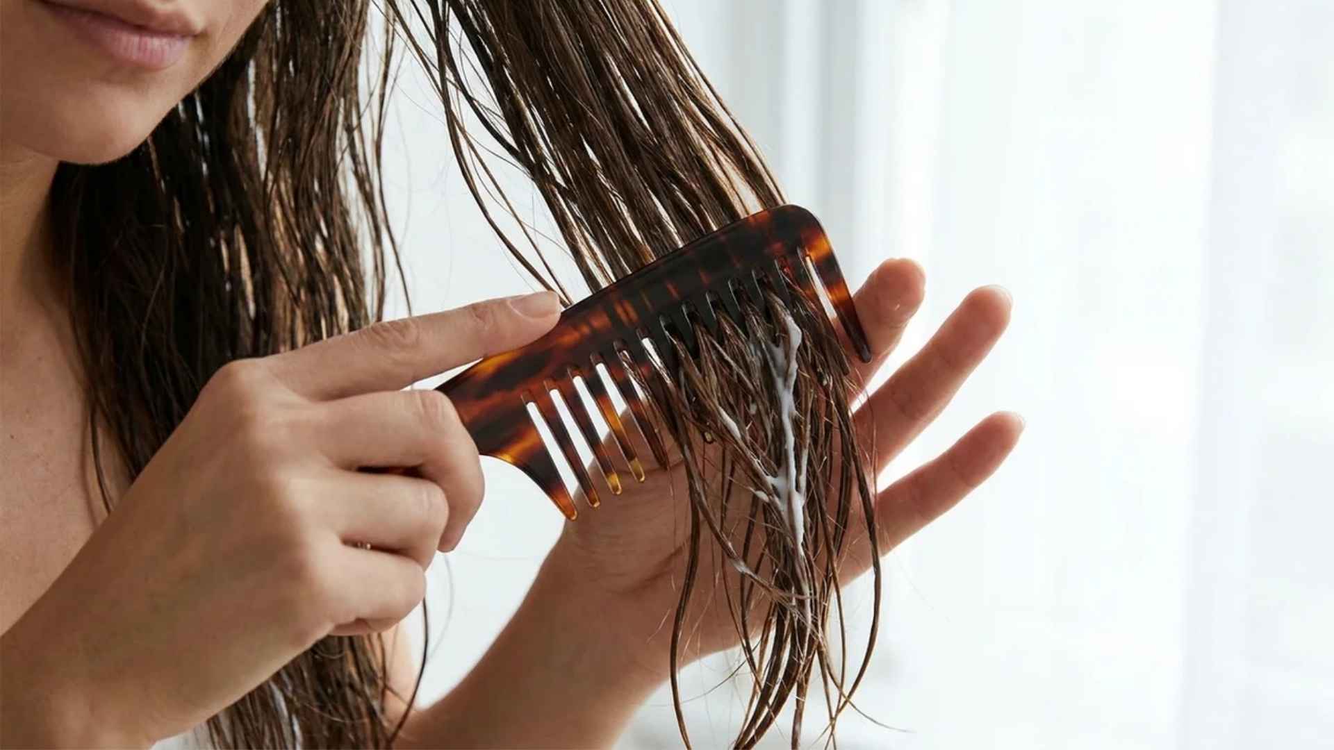 Wide tooth comb gently detangling damp hair strands to reduce pulling and breakage