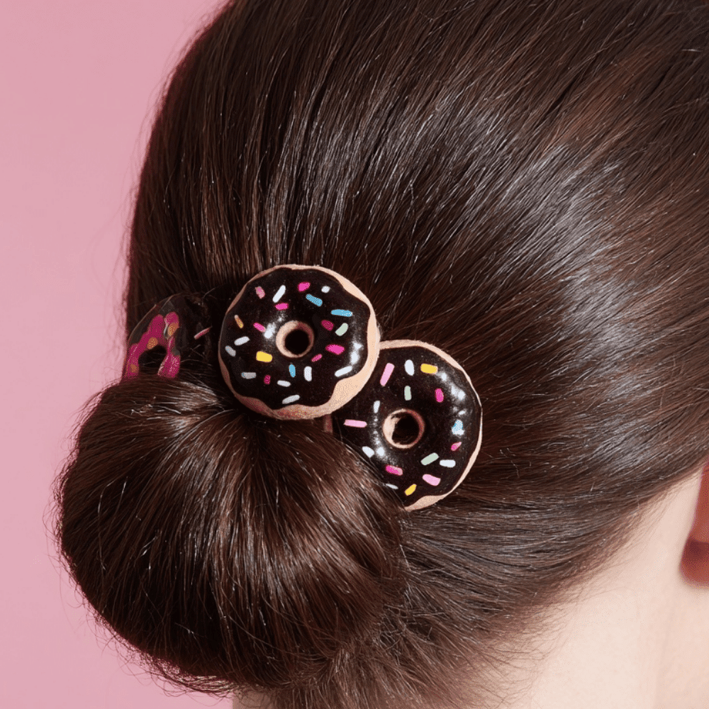 Close up of bun hairstyle decorated with colorful donut clips and sprinkle details.