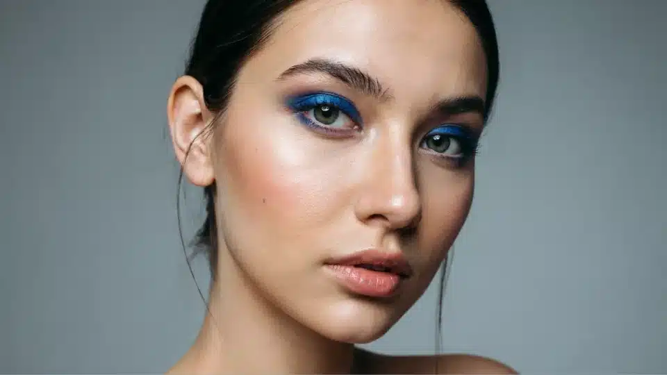 Woman wearing electric blue eyeshadow applied lightly for a fresh colorful everyday makeup look.
