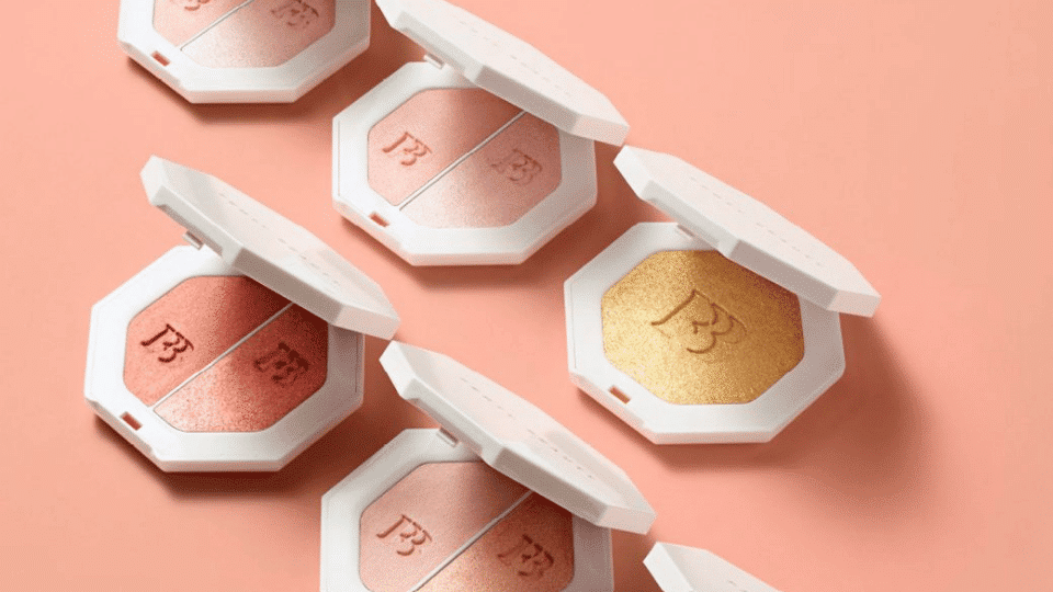 Open Fenty Beauty Killawatt Freestyle Highlighter compacts in multiple shades arranged on a peach background surface
