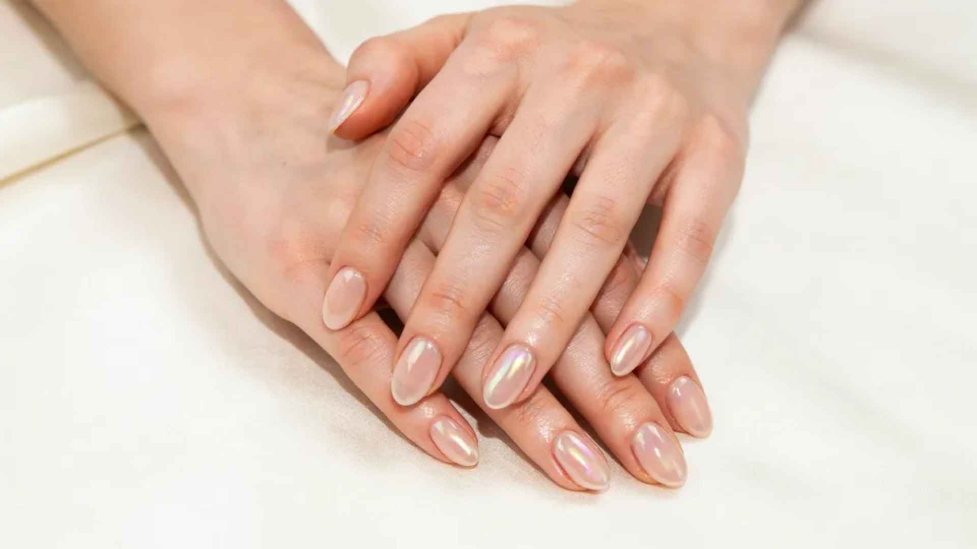 Long almond glazed donut nails with a soft chrome finish creating an elegant glossy pearl manicure style