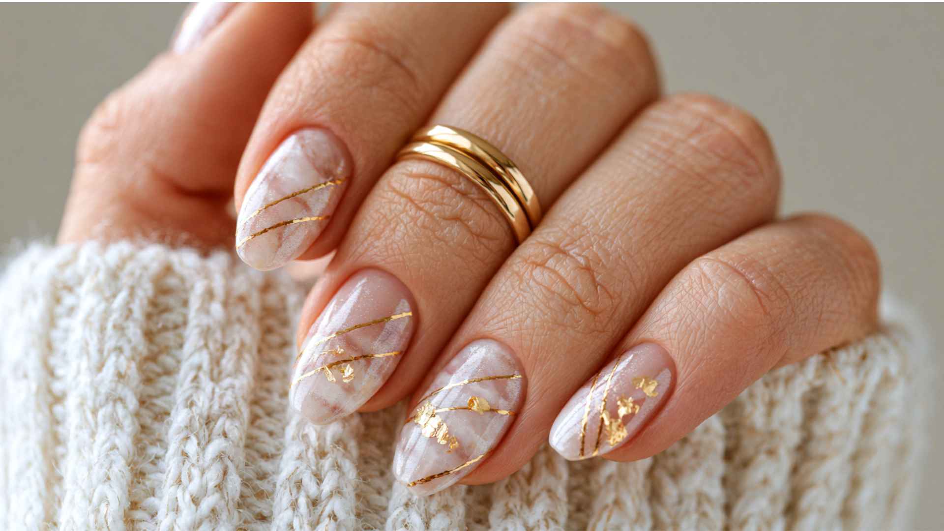 Close up of glazed donut nails with fine gold accents over a sheer pearl chrome base and a clean glossy finish