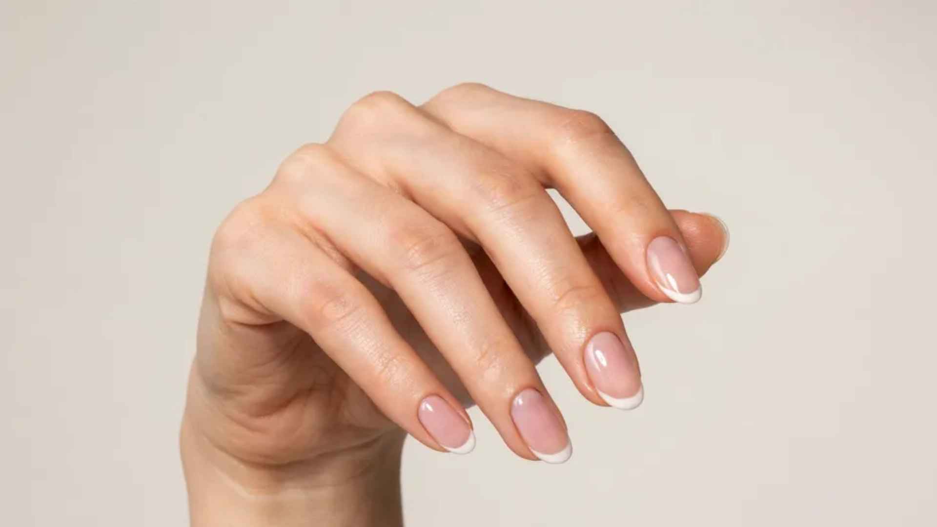 Close up of glazed donut ombre nails blending sheer nude into white tips with a glossy pearl chrome finish in daylight