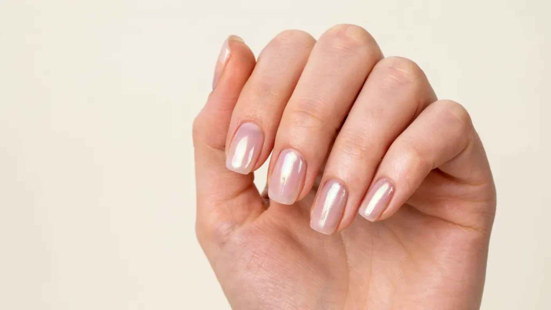 Close-up of square glazed donut nails with clean edges, a sheer nude base, and a smooth glossy chrome finish in daylight