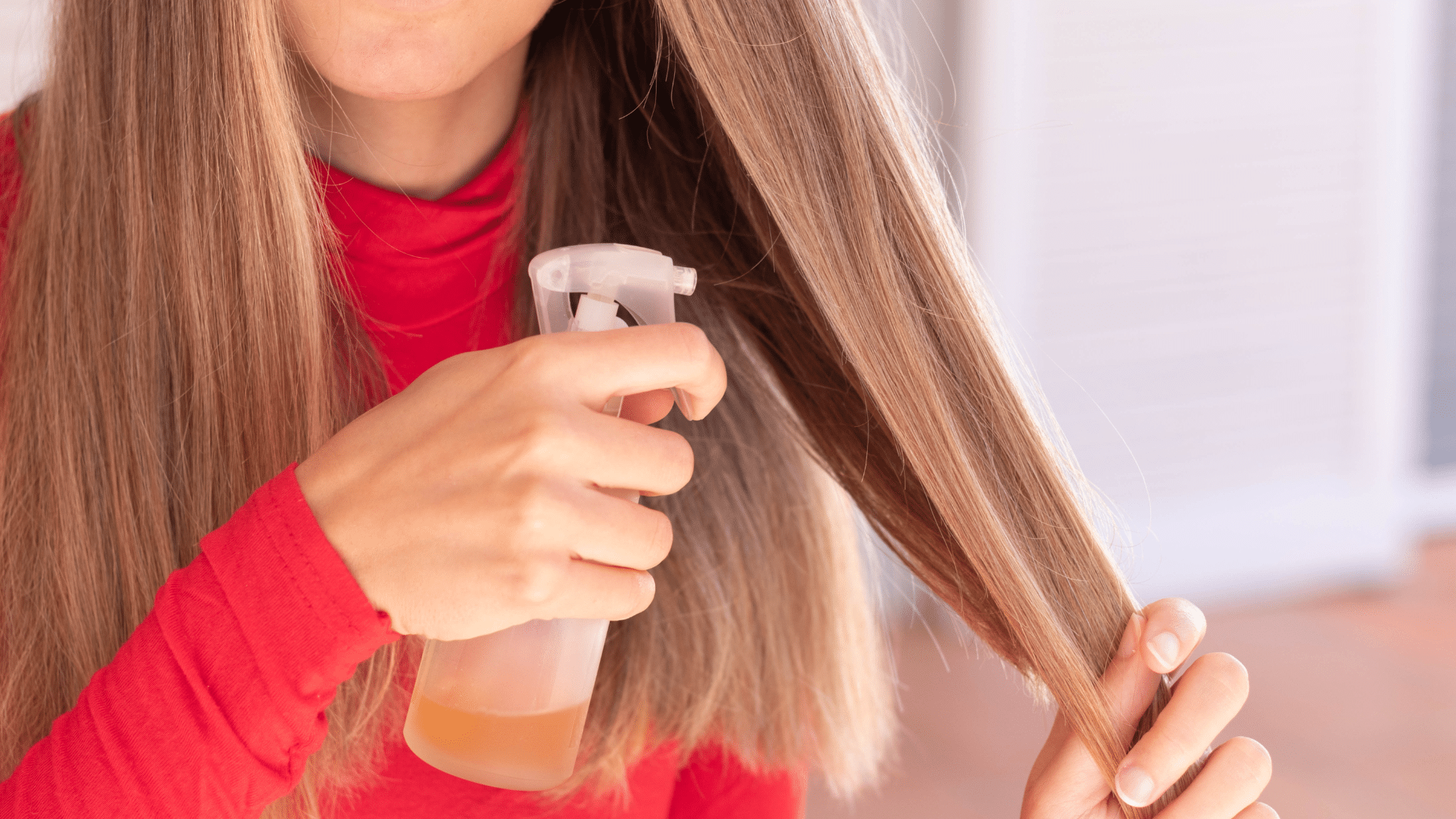 Woman applying gloss or toner spray to hair strands for color refresh and shine enhancement.