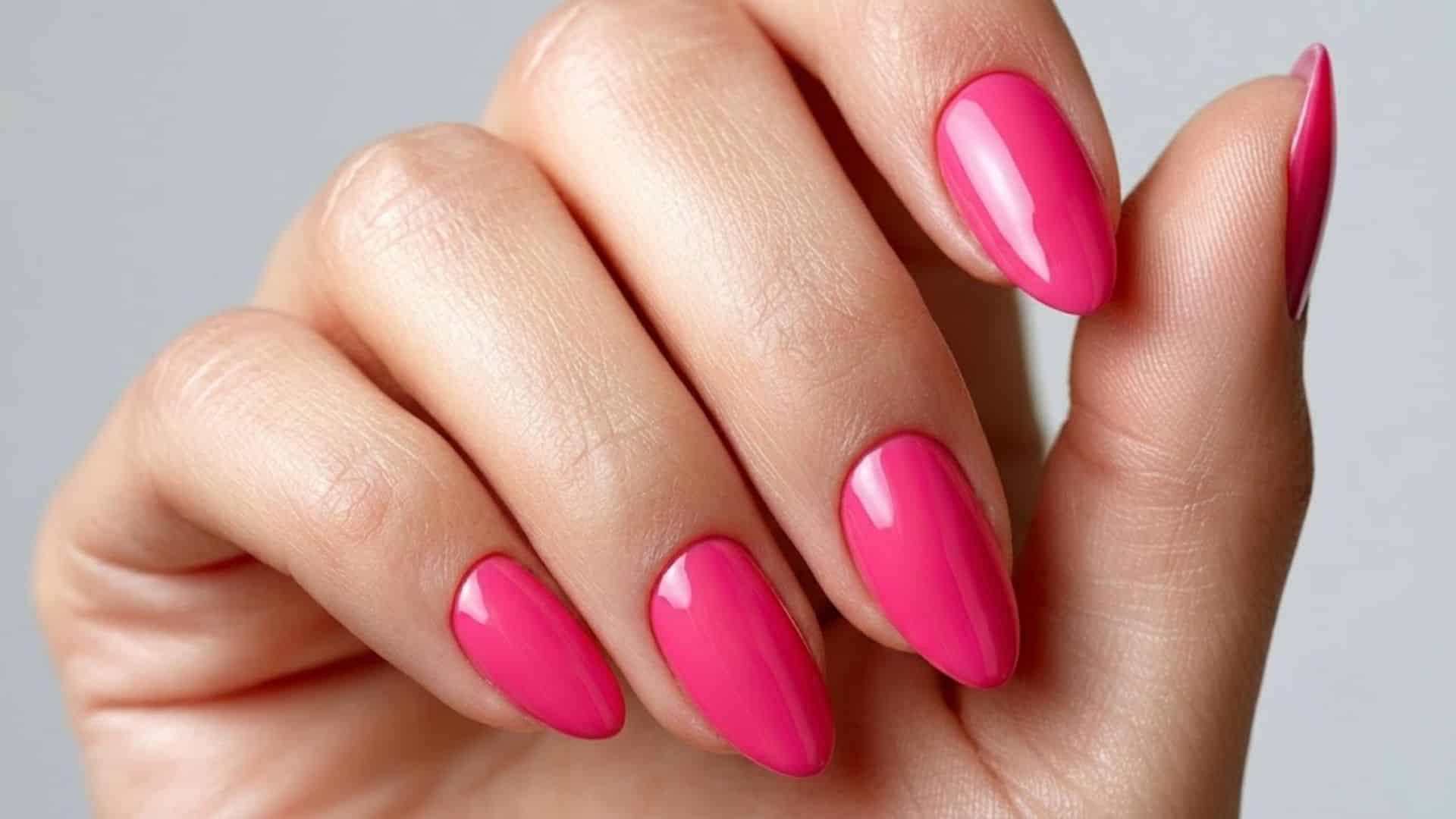 Close up of hand with hot pink almond shaped nails in high glossy finish