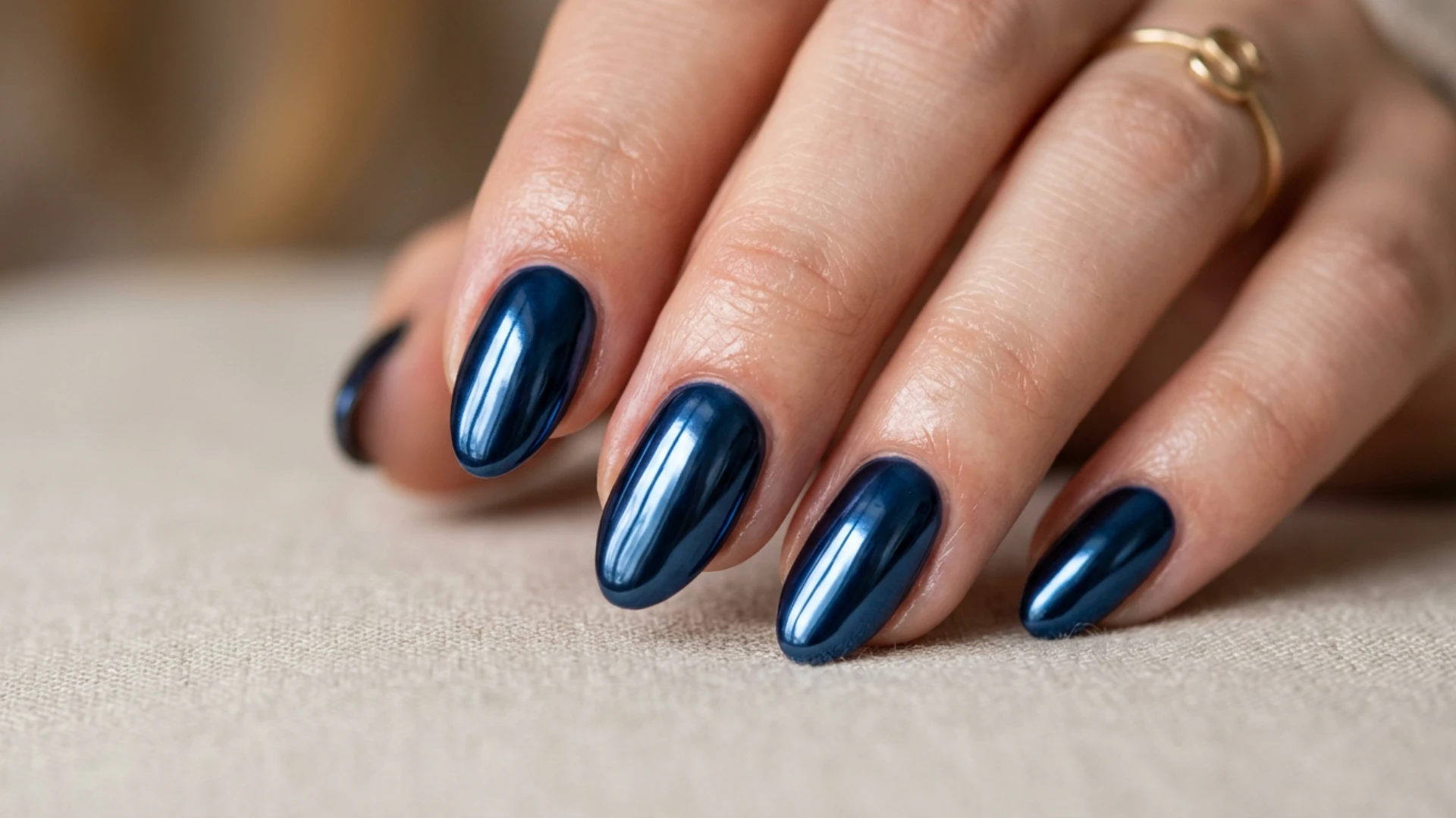 Stylish navy manicure featuring smooth oval nails coated in rich blue polish with a shiny elegant appearance
