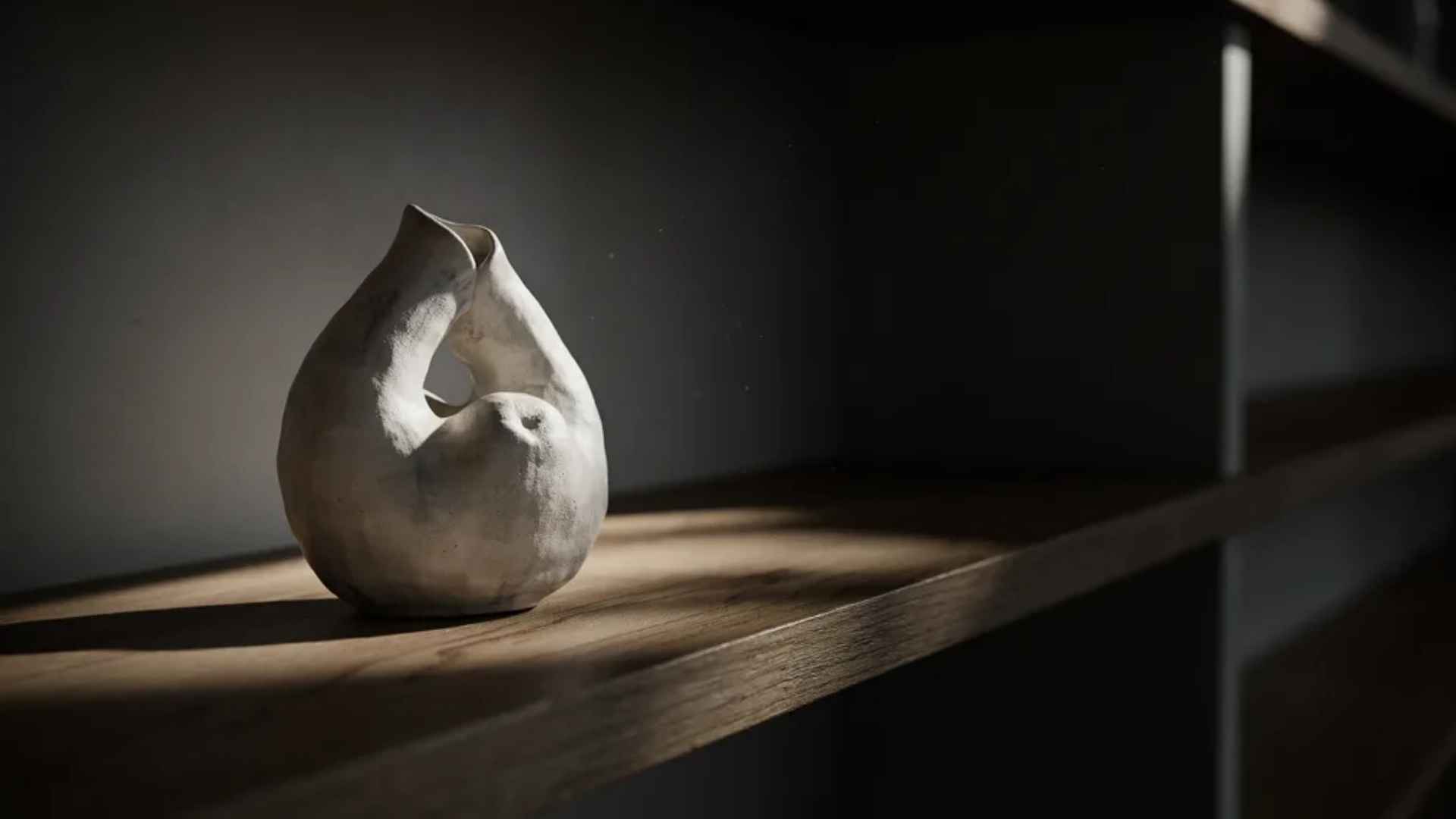 Abstract ceramic sculpture anchoring a styled bookshelf section