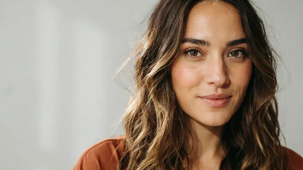 Brown hair with golden blonde balayage highlights styled in relaxed waves with a smooth natural finish