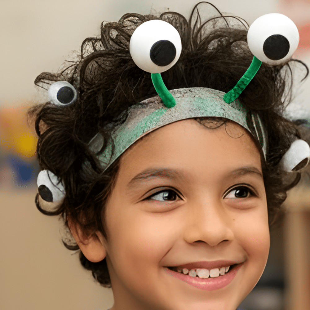 Smiling child wearing a googly eye monster headband with a playful crazy hair style.