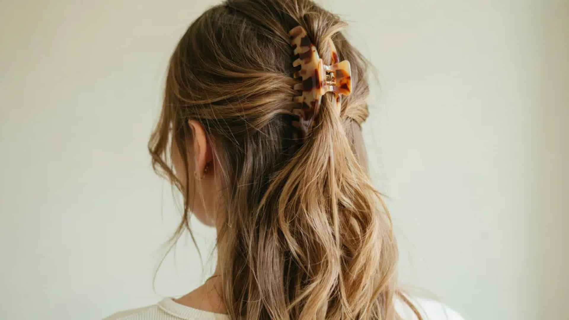 Half-up Y2K hairstyle secured with a large claw clip and loose flowing hair.