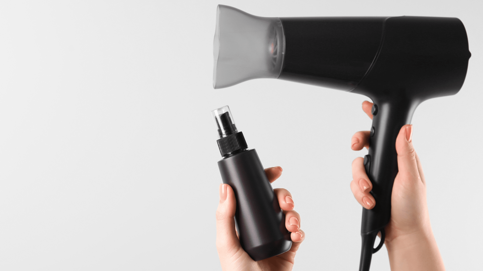 Heat styling tools with a hair dryer and styling spray being used for hair care.