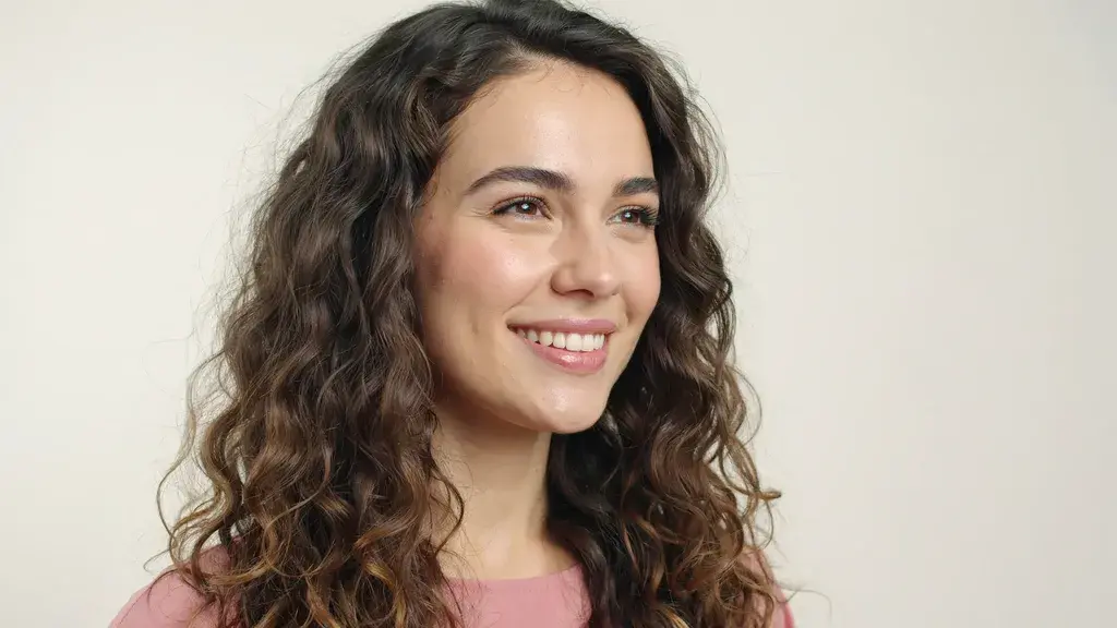 Dark brown curly hair with natural waves styled in a voluminous layered cut with soft texture and defined curl pattern