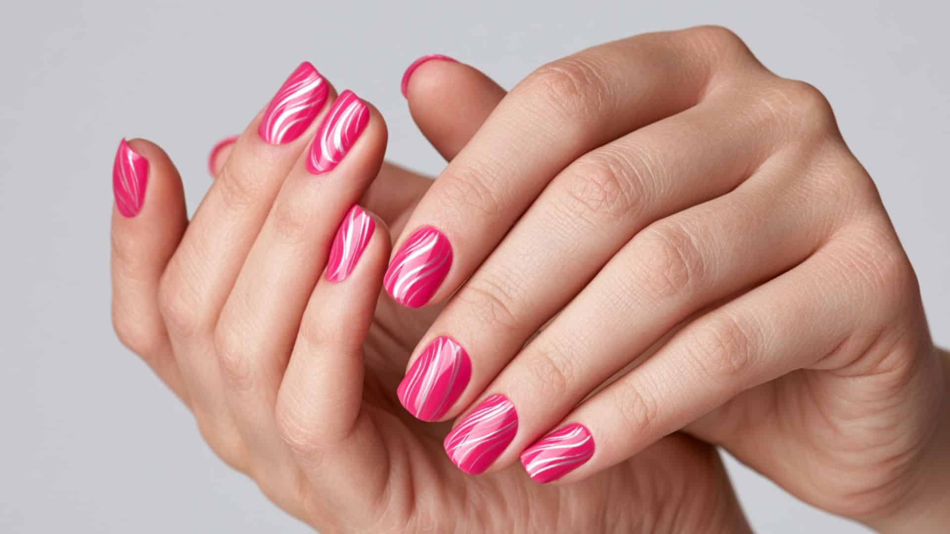 Hot pink nails with white and silver swirling line nail art.