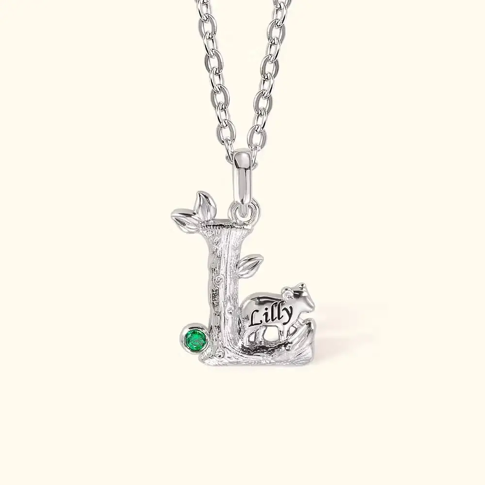 Silver pendant in the shape of a tree with green gemstone on chain