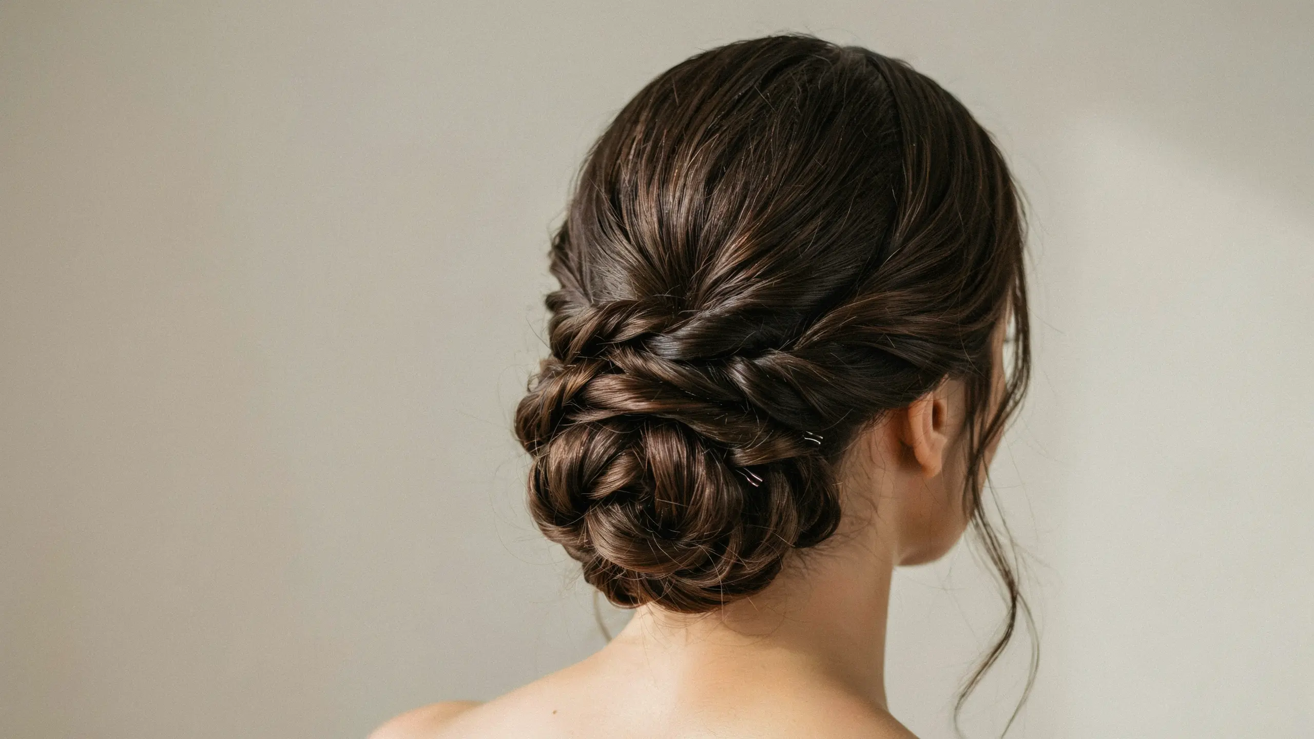 Long hair styled into an elegant braided low bun updo with textured details