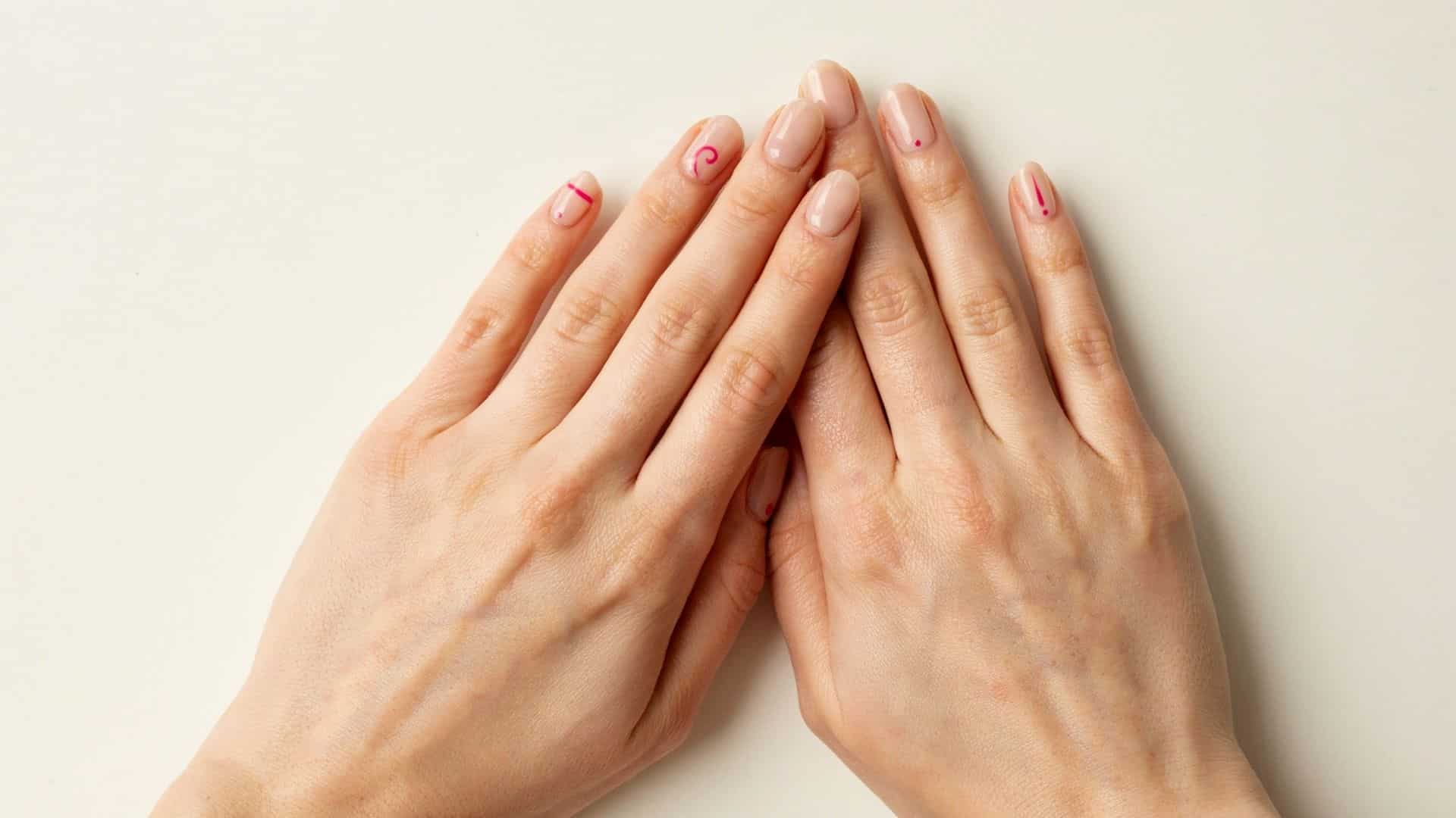 Nude nails with tiny minimalist hot pink line, dot, and swirl accents.
