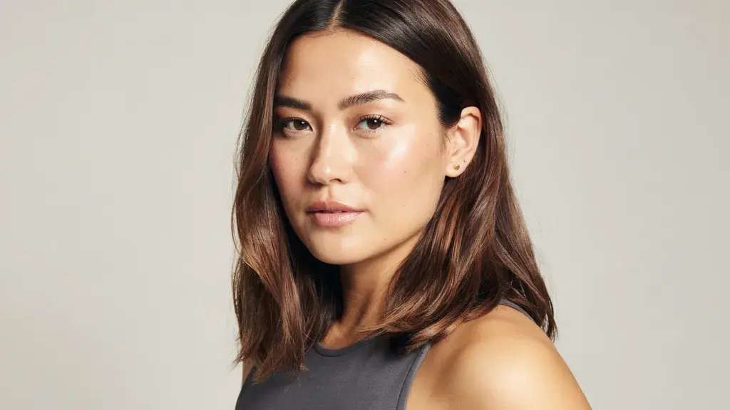 Dark brown hair with subtle warm highlights styled in a smooth shoulder length layered cut with natural shine and texture