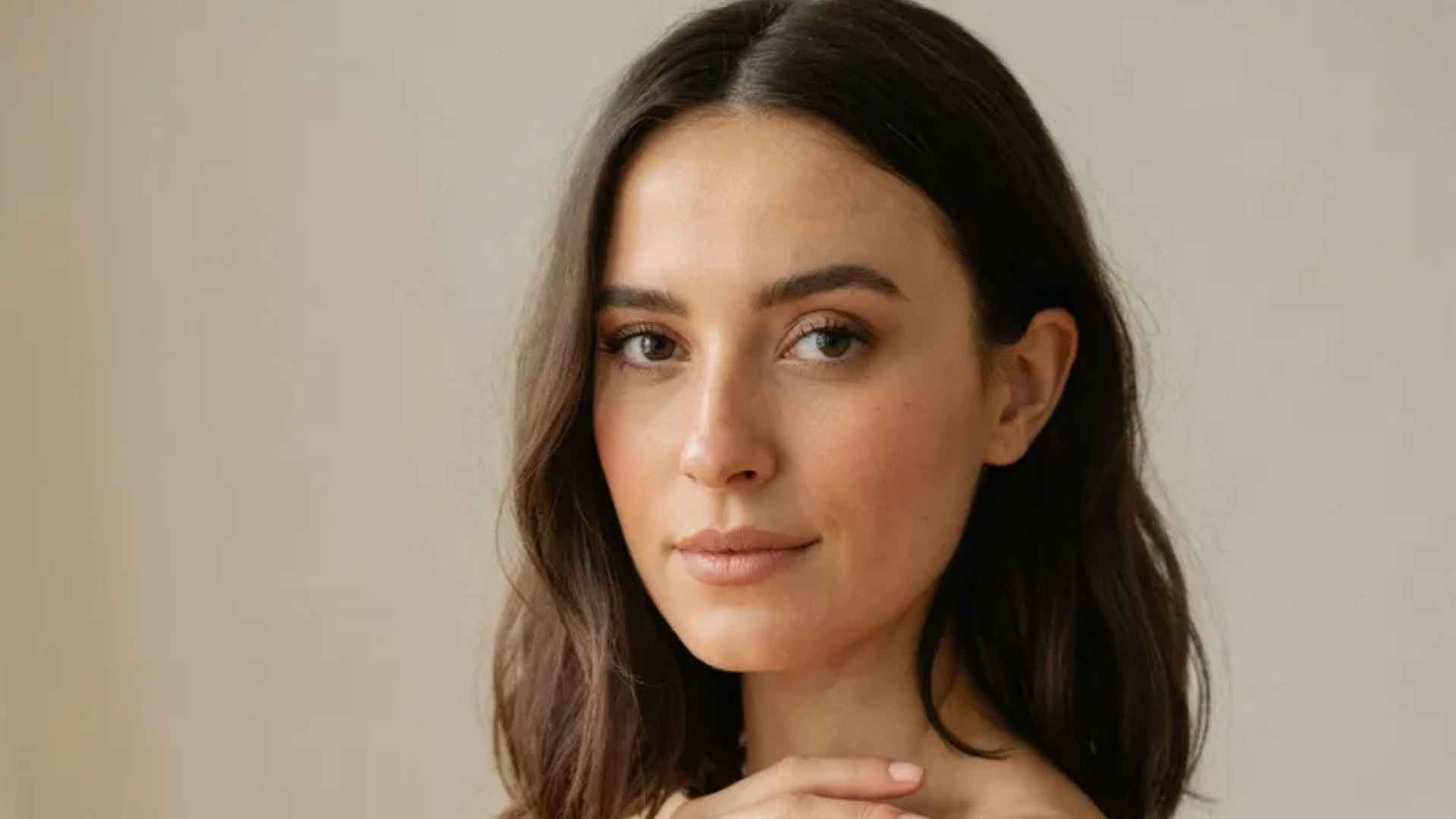 Woman wearing natural brown makeup with soft eyeshadow, defined lashes, warm tones, and a nude lip finish