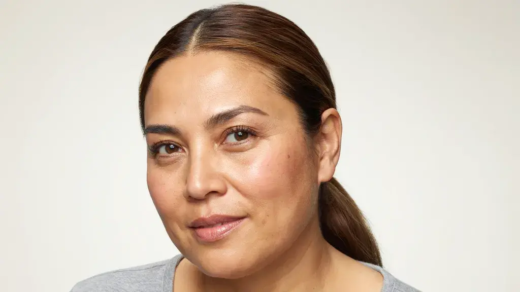 Sleek brown hair pulled into a low ponytail with a smooth finish and subtle warm highlights for an elegant hairstyle look