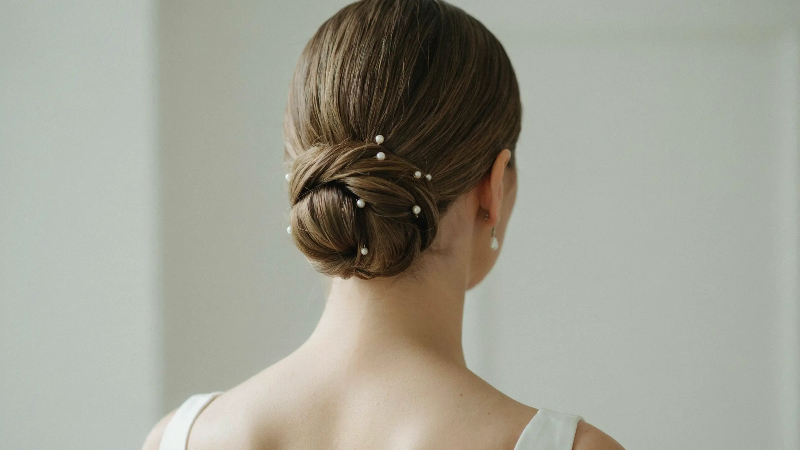 Pearl pin accented low bun, one of many elegant updo hairstyles