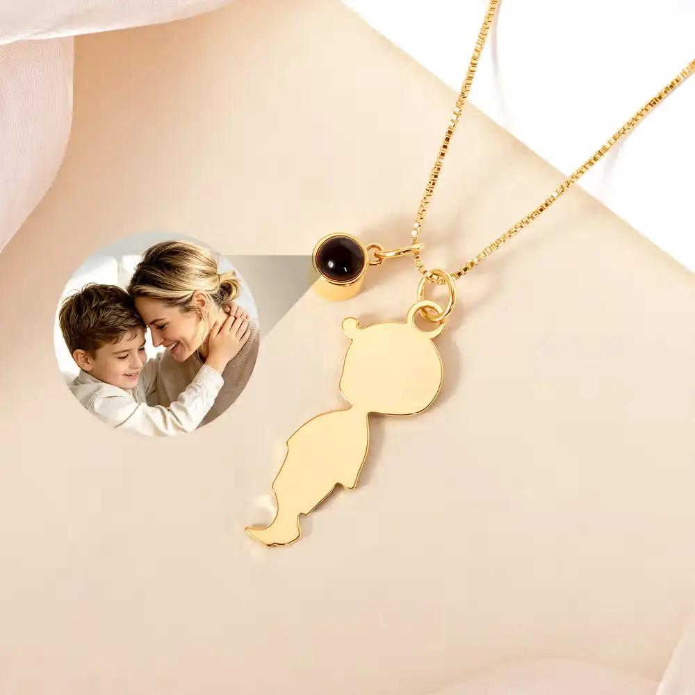 Gold boy-shaped pendant necklace with black stone charm on neutral background