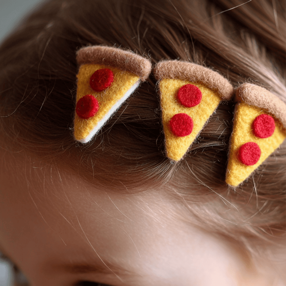 Close up of hair decorated with felt pizza slice clips for a fun food themed style.